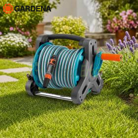 Compact garden hose reel with hose and accessories on lawn in a flower garden